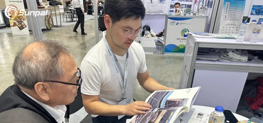 Two men reviewing a solar energy brochure at a trade show booth.