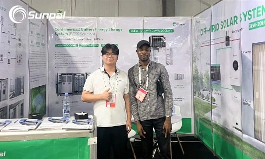 Two people standing in a Sunpal exhibition booth with solar energy posters and product displays at Nigeria Energy 2025.