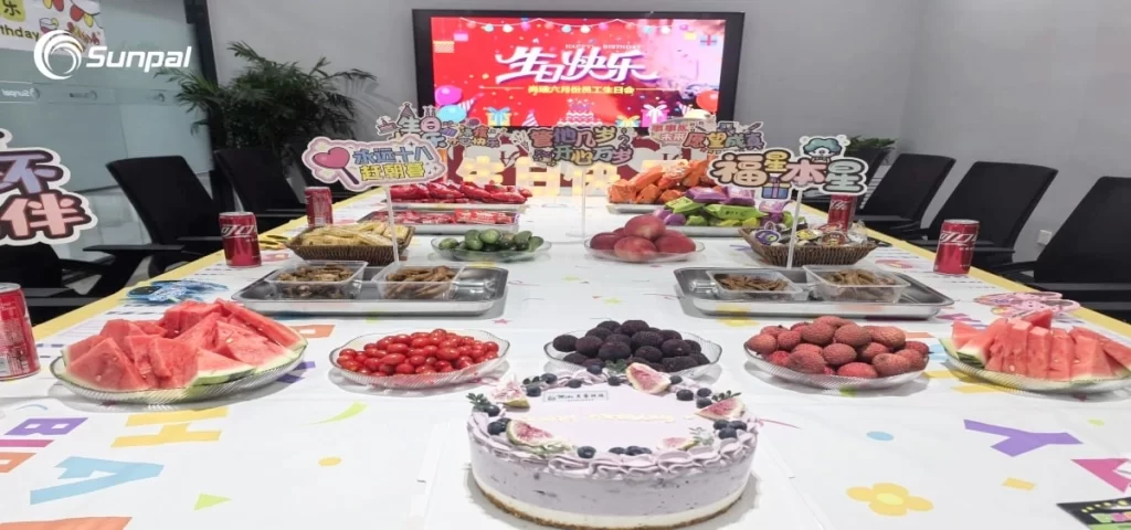 Sala conferenze decorata con scritte e cibo di compleanno, con una torta di compleanno e rinfreschi per festeggiare il team.
